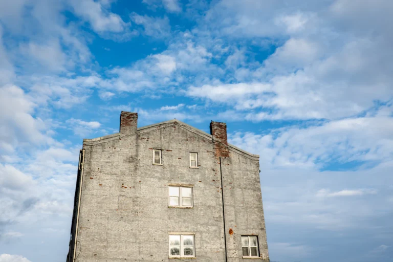 Weathered brick facade of an older building against the sky, the kind of wall whose parapet needs a yearly observation