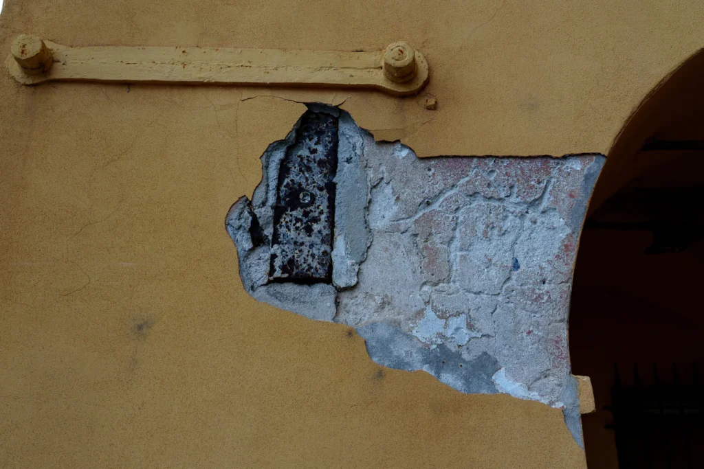 Spalled concrete with exposed rusted rebar that needs removal to clean steel before a garage concrete repair