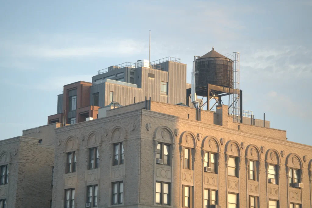 Brick building rooftop in New York with a wooden water tower, the kind of roof edge an annual parapet inspection covers