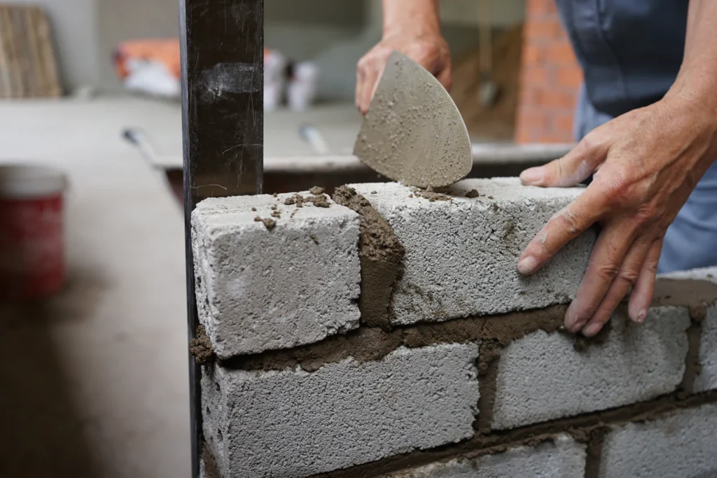 Fresh mortar being applied to a brick wall, the kind of repointing work a parapet often needs after its observation