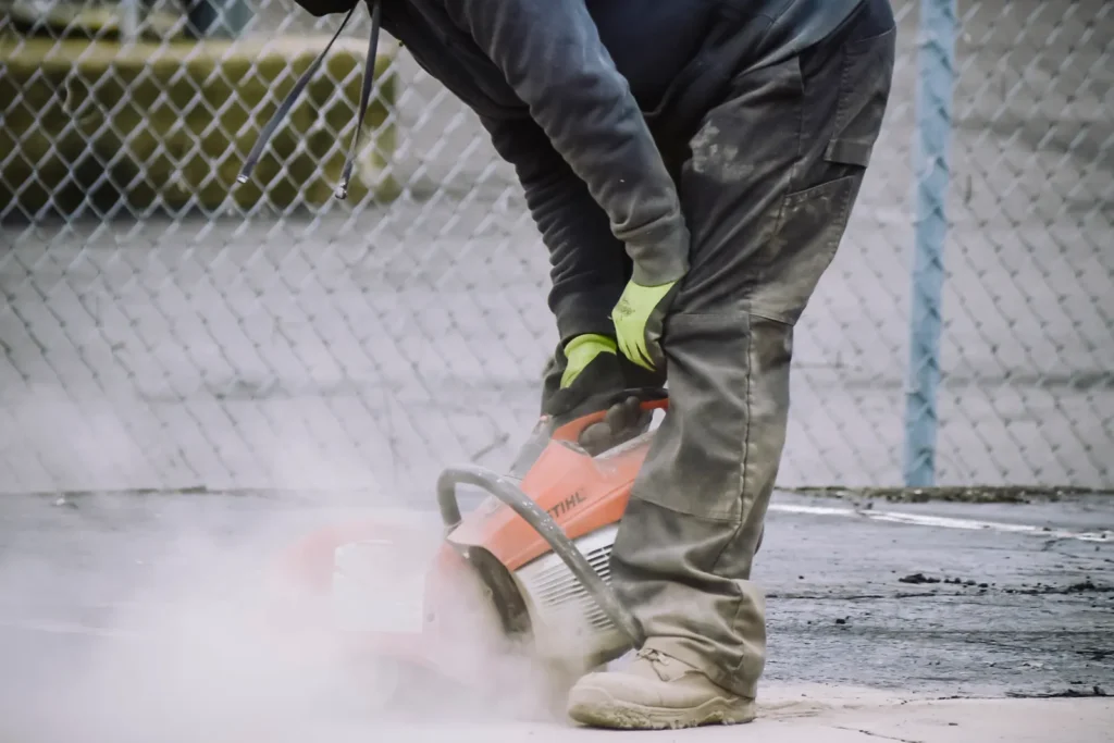 Worker in safety gear cutting out damaged concrete during repairs that clear a Local Law 126 violation
