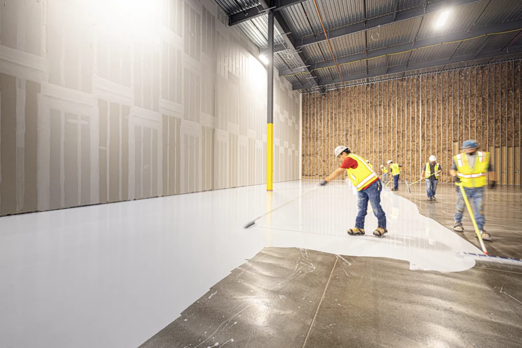 Crew rolling a protective waterproof coating across a concrete deck for parking garage waterproofing in NYC
