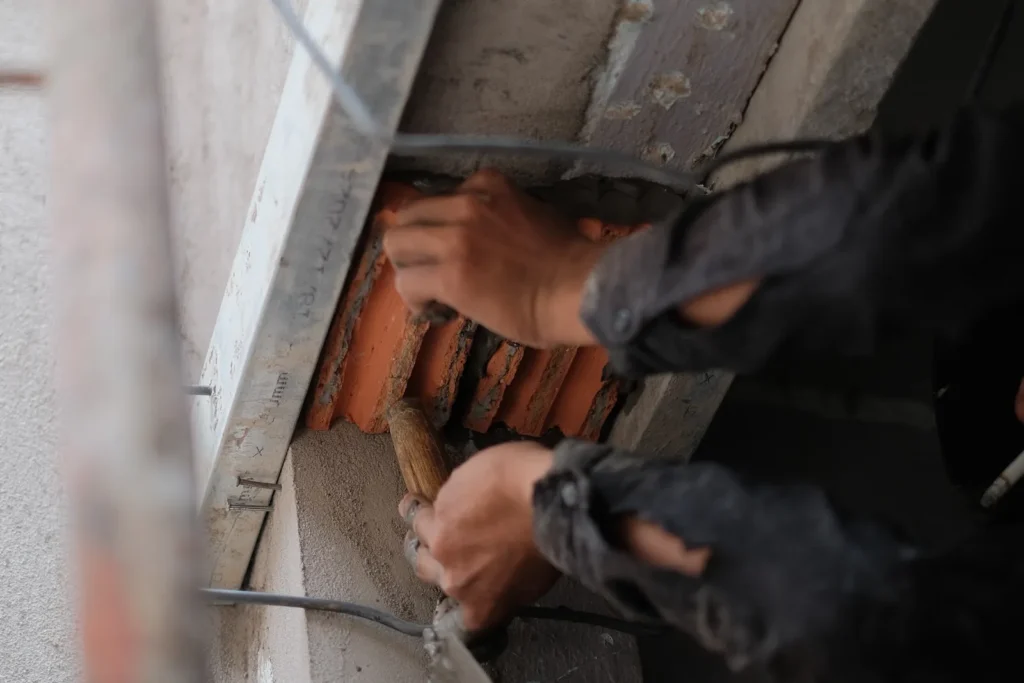 Contractor repairing a concrete surface with a trowel to clear SREM conditions in a NYC parking garage