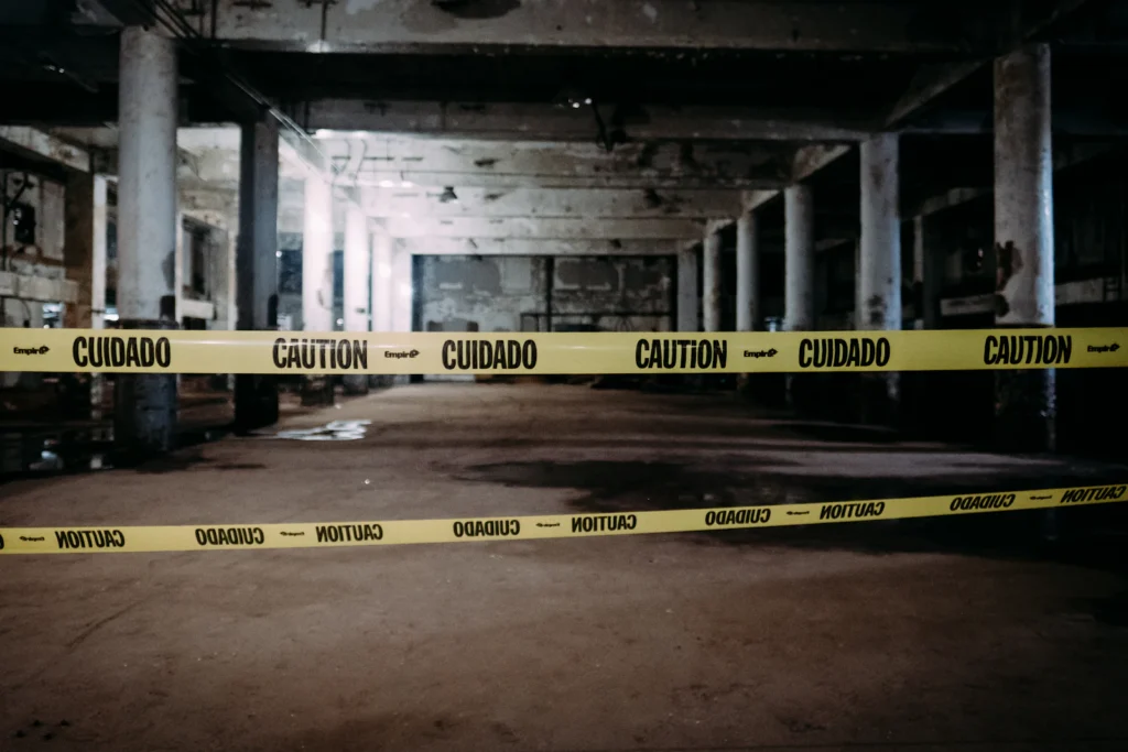 Caution tape cordoning off an Unsafe area between concrete columns in a parking garage before repairs